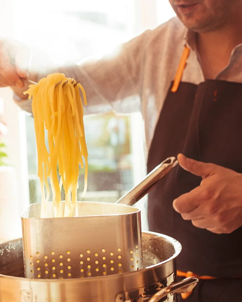 Frisch gekochte Spaghetti werden mit der Gabel aus dem Topf gehoben